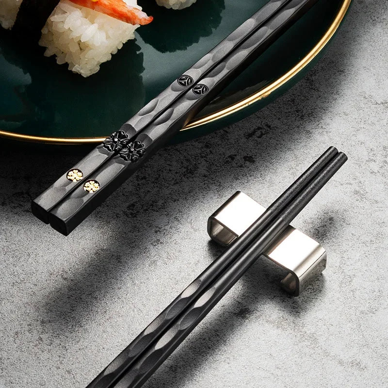 Baguettes noires Matsue posées sur un repose-baguettes avec des sushis